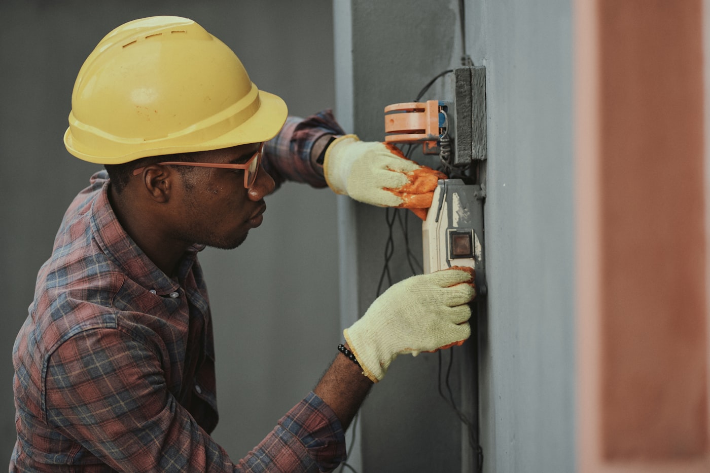 An electrician in a hard hat working on a home's panel